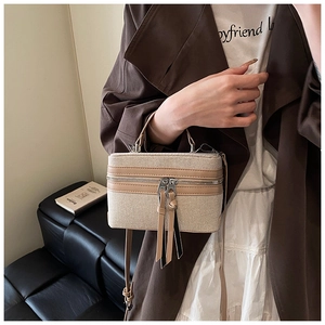 Detail of contrast stitching box bag featuring beige canvas and brown leather trim