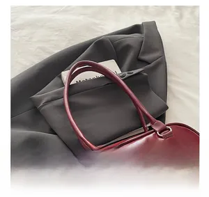 Macro view of burgundy Boston bag showing metal buckles and dual front pockets