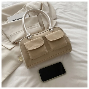 Détail d'un sac à main kaki vintage avec deux poches à rabat et des poignées blanches
