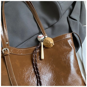 Detail of vintage brown tote bag texture with creative baseball charms on a grey blazer