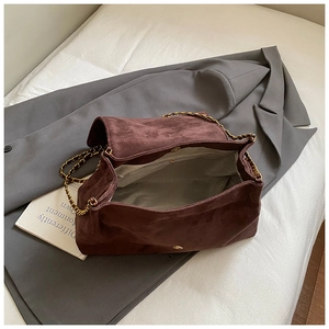 Detail view of suede chain bag with gold hardware and interior zipper pocket