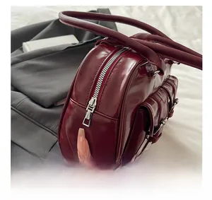 Detail of silver smooth zipper and side buckle on burgundy faux leather handbag
