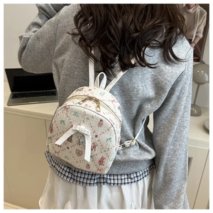 Gros plan d'un mini sac à dos blanc avec motifs floraux et pendentif en cœur et nœud