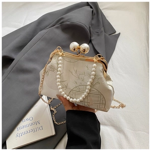Close-up of vintage embroidery bag with pearl handle, gold chain and bamboo pattern