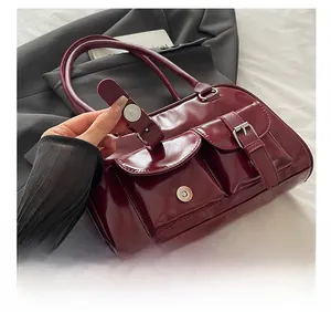 Detail of dark red patent leather bowling bag featuring front pockets and silver hardware