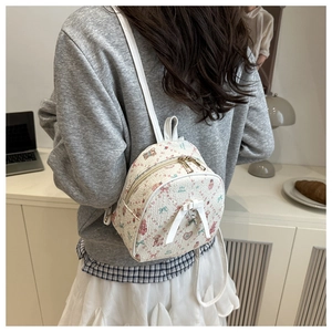 Close-up of a white mini backpack with pink bear prints and a bow on a model