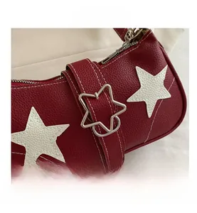 Detail of red pebbled leather shoulder bag with white star patch and silver star buckle