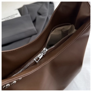 Detail of silver metal zipper and dark brown leather texture on large tote bag