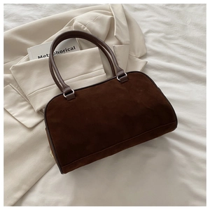 Vue détaillée de la texture en daim marron foncé et des lanières en cuir du sac rétro