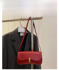 Detail of red leather shoulder bag with gold metal buckle hanging on a suit