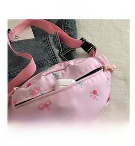 Detailed view of pink floral crossbody bag with bow patterns and adjustable strap