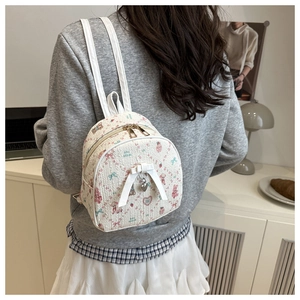 Gros plan du mini sac à dos floral avec nœud et breloque cœur sur un mannequin