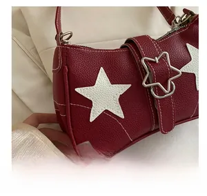 Detail of burgundy pebbled leather bag with white star patch and star metal buckle