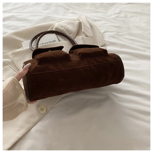 Détail du sac à main en daim marron foncé avec poches à rabat et poignée courbée