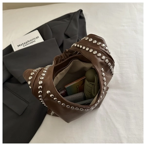 Detail of spacious dark brown leather bag interior showing daily items and metal studs