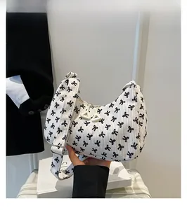 Dettaglio borsa a spalla in velluto bianco con motivi a fiocco e cerniera a triangolo