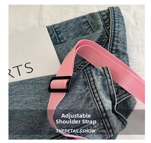 Detail of pink adjustable nylon shoulder strap with matte black buckle on crossbody bag