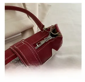 Detail of red pebbled leather underarm bag with white stitching and silver metal zipper