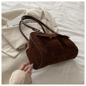 Détail d'un sac cylindre en daim marron foncé avec poches utilitaires et bandoulière longue