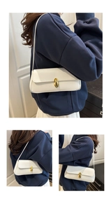 Close-up of creamy white baguette bag with gold metal twist lock and lychee texture