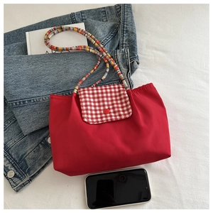 Détail du sac cabas en nylon rouge avec rabat à carreaux et bandoulière en perles