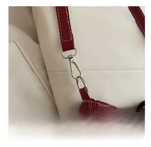 Detail of red lychee grain leather strap with silver swivel hook and white contrast stitching