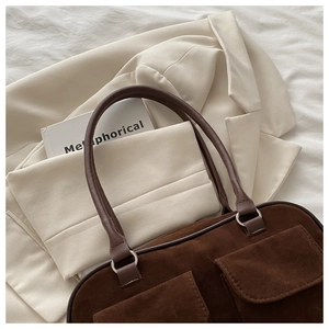 Détails d'un sac à main en daim marron avec poches à rabat et poignées en cuir vintage