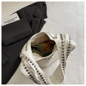 Detail view of white leather shoulder bag with silver studs and spacious interior