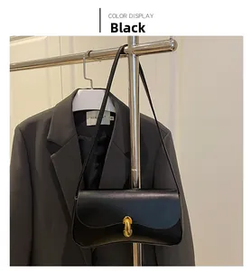 Detail of elegant black shoulder bag with a prominent gold metal clasp on a leather flap