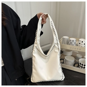 Detail of white hobo bag featuring silver rivet trim and smooth faux leather texture