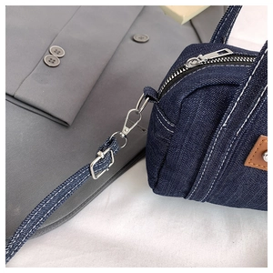 Close-up of silver metal hardware and white stitching on navy washed denim bag