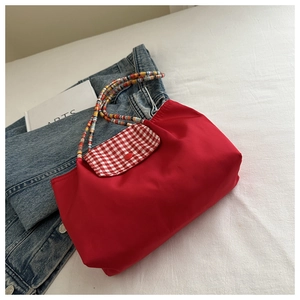 Détail du cabas rouge en nylon avec rabat à carreaux rouge et blanc et bandoulière en perles