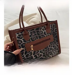 Dettaglio della borsa leopardata con manici in pelle marrone e cerniera dorata