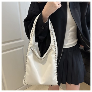 Detail of white PU leather shoulder bag with decorative silver rivets and U-shaped design