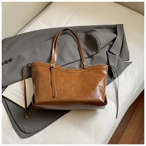 Detail of glossy caramel brown tote bag with premium leather texture and long straps
