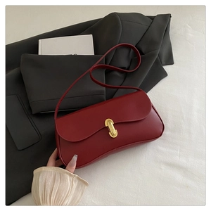 Close-up of wine red leather shoulder bag with sleek gold lock and clean rectangular shape