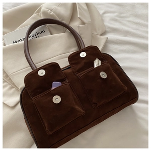 Détail d'un sac à main en daim marron foncé avec deux poches frontales à boutons aimantés
