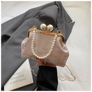 Close-up of vintage pink floral embroidery bag with pearl handle and metal clasp