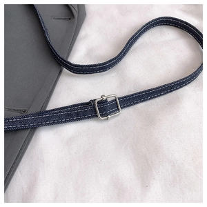 Detail of dark blue denim strap with white contrast stitching and silver metal buckle