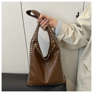 Detail of dark brown faux leather tote bag with silver metallic rivet stud decorations