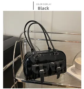 Detail of glossy black faux leather shoulder bag with silver buckles and retro pockets
