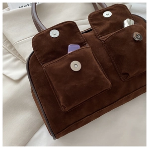 Détail du sac à main en daim marron foncé avec deux poches avant et boucle magnétique argentée
