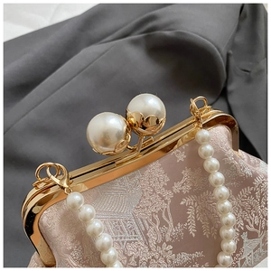 Nahaufnahme der rosa Sticktasche mit Goldrahmen und elegantem Perlengriff-Detail