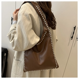 Detail of caramel leather hobo bag with silver stud accents and bohemian style