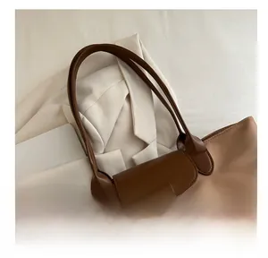 Dettaglio della borsa tote in nylon marrone con patta in pelle e manici robusti