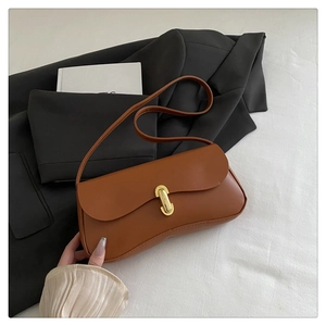 Detail of a brown leather shoulder bag featuring a gold U-shaped buckle and fine stitching