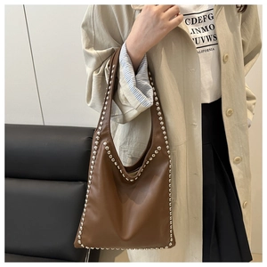 Detail of caramel brown leather shoulder bag with silver rivet trim on the strap