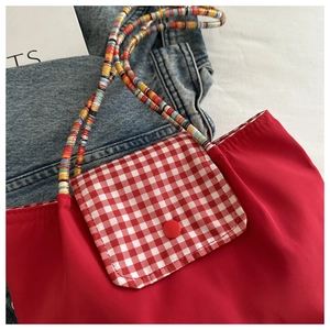 Détail du sac cabas en nylon rouge avec poche à carreaux et poignée tressée colorée
