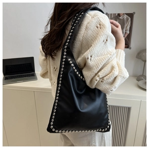 Close-up of black soft leather tote with silver rivet studs in a lifestyle office setting