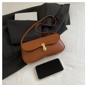 Close-up of brown leather baguette bag with vintage gold buckle on black blazer